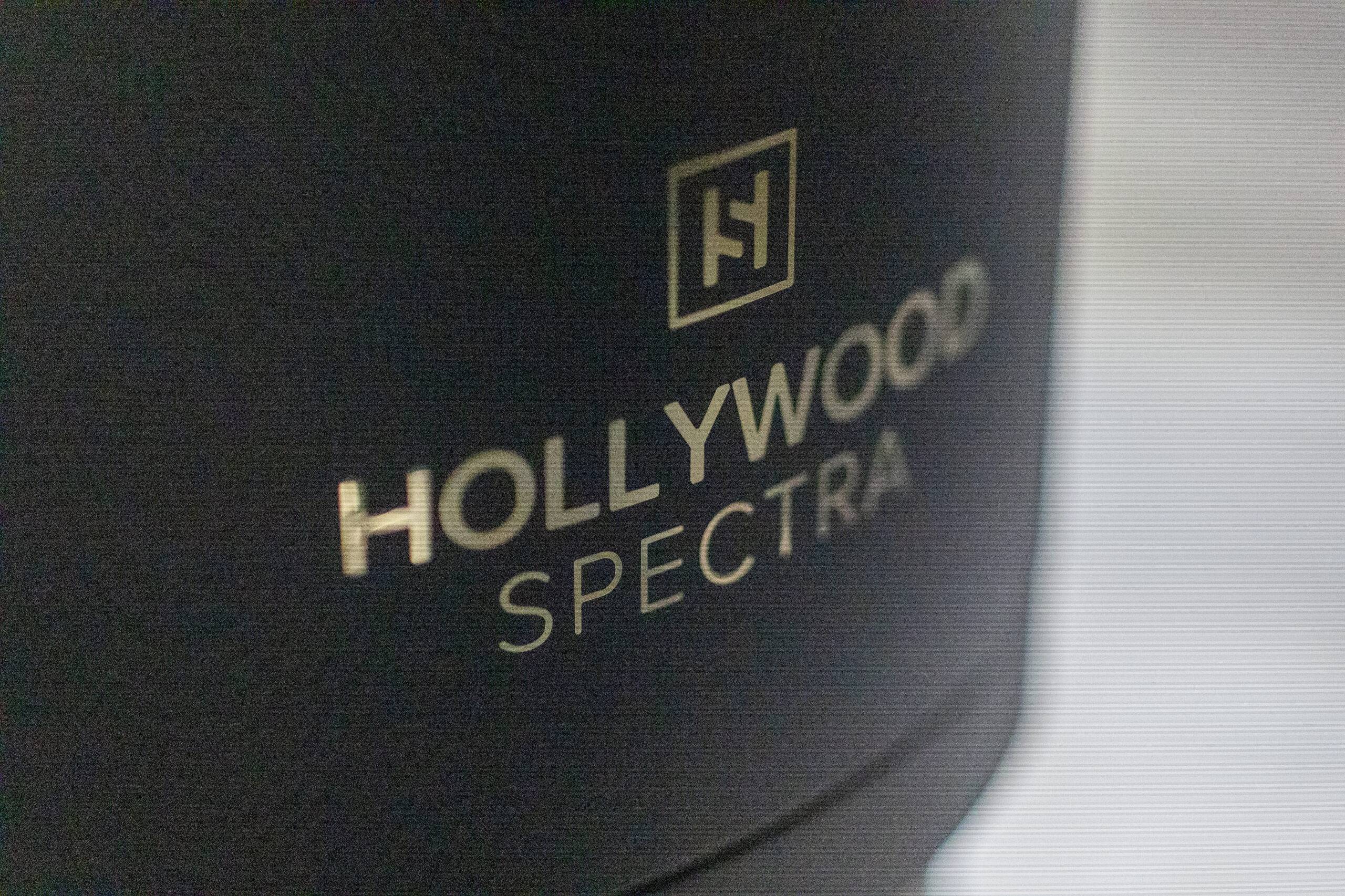Close-up view of a black cylindrical object labeled "Spectra Laser" and a square logo featuring the letters "hj" printed in white.