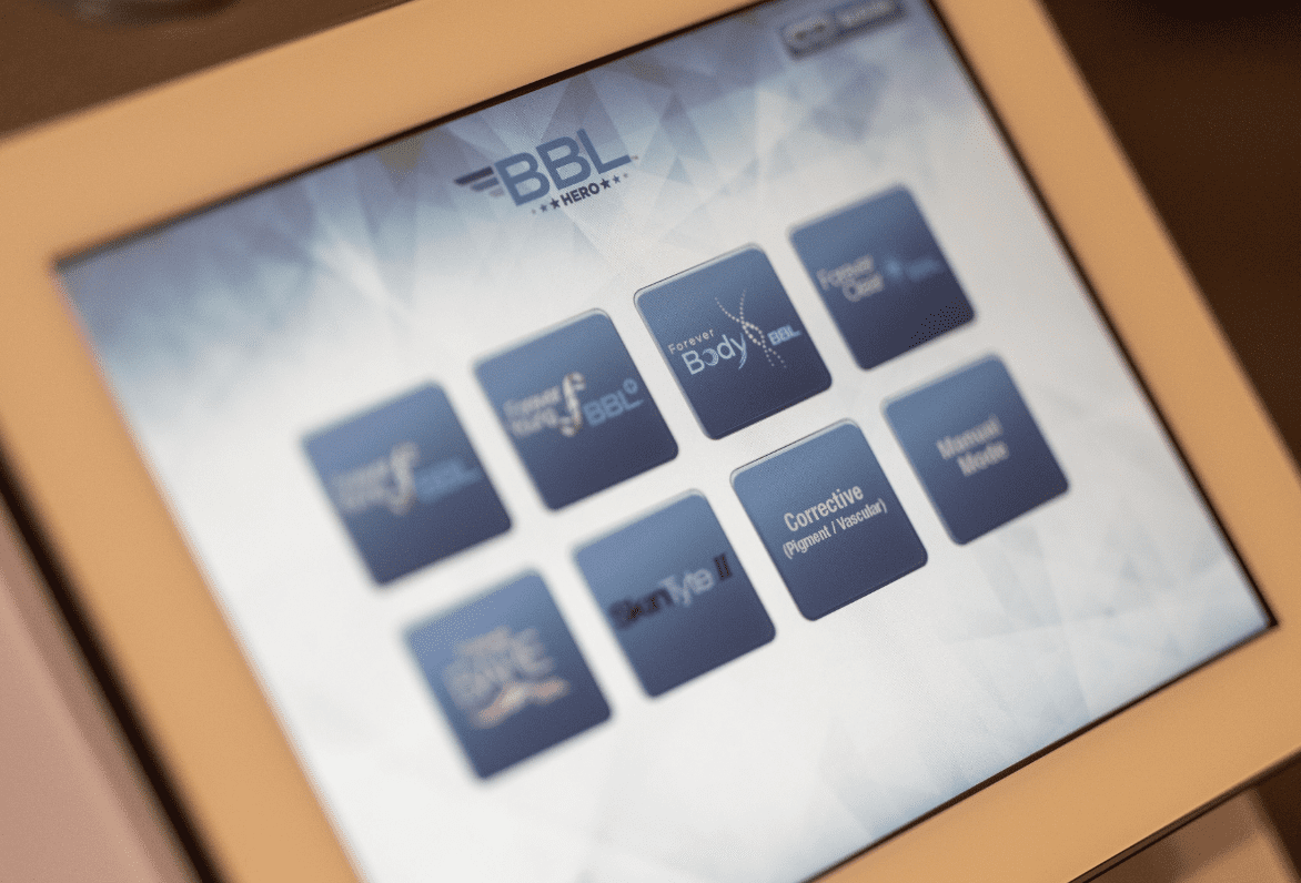 A close-up of a digital tablet screen displaying various application icons related to medical and health services, including BroadBand Light Therapy for skin rejuvenation, with a focus on clarity and technology interface.