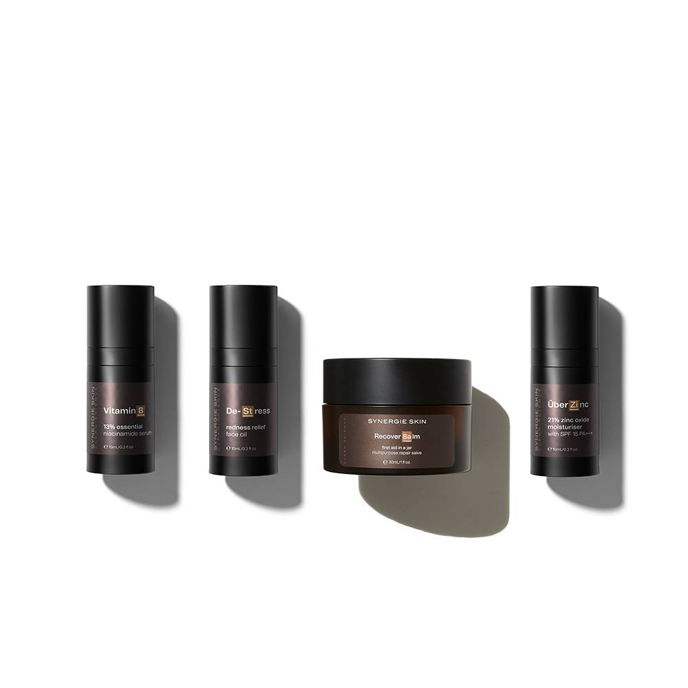 Four skincare products from the Synergie Skin Post-Treatment Kit, including three cylindrical containers and one round jar, are systematically arranged on a light background with shadows. Each item is labeled with its specific use.