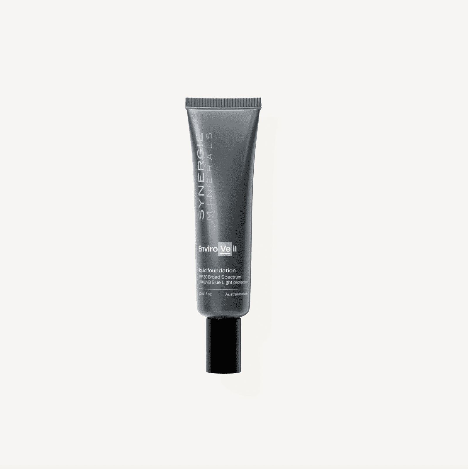 A tube of synergie minerals enviroveil ii nude foundation displayed upright against a white background. the packaging is sleek and black with white text detailing the product information.