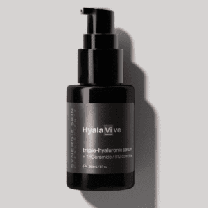 A dark bottle labeled "hyla vive triple-hyaluronic serum" with a pump dispenser, shown in partial shadow on a light background.