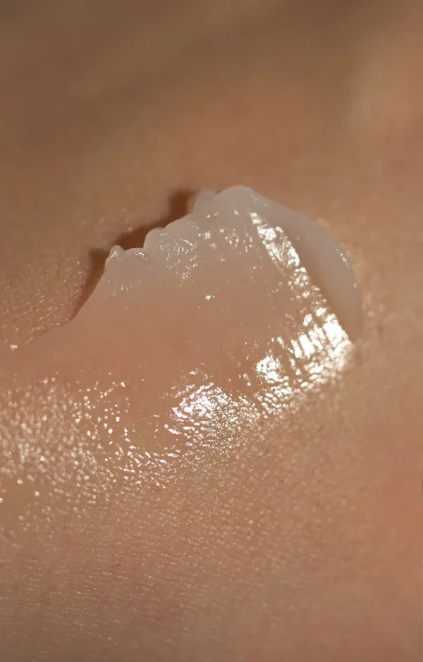 A close-up of Clear as Day SPF50+ Dreamscreen 75ml sunscreen gel applied on smooth, light-toned skin, showcasing a glossy, hydrated finish under direct light.