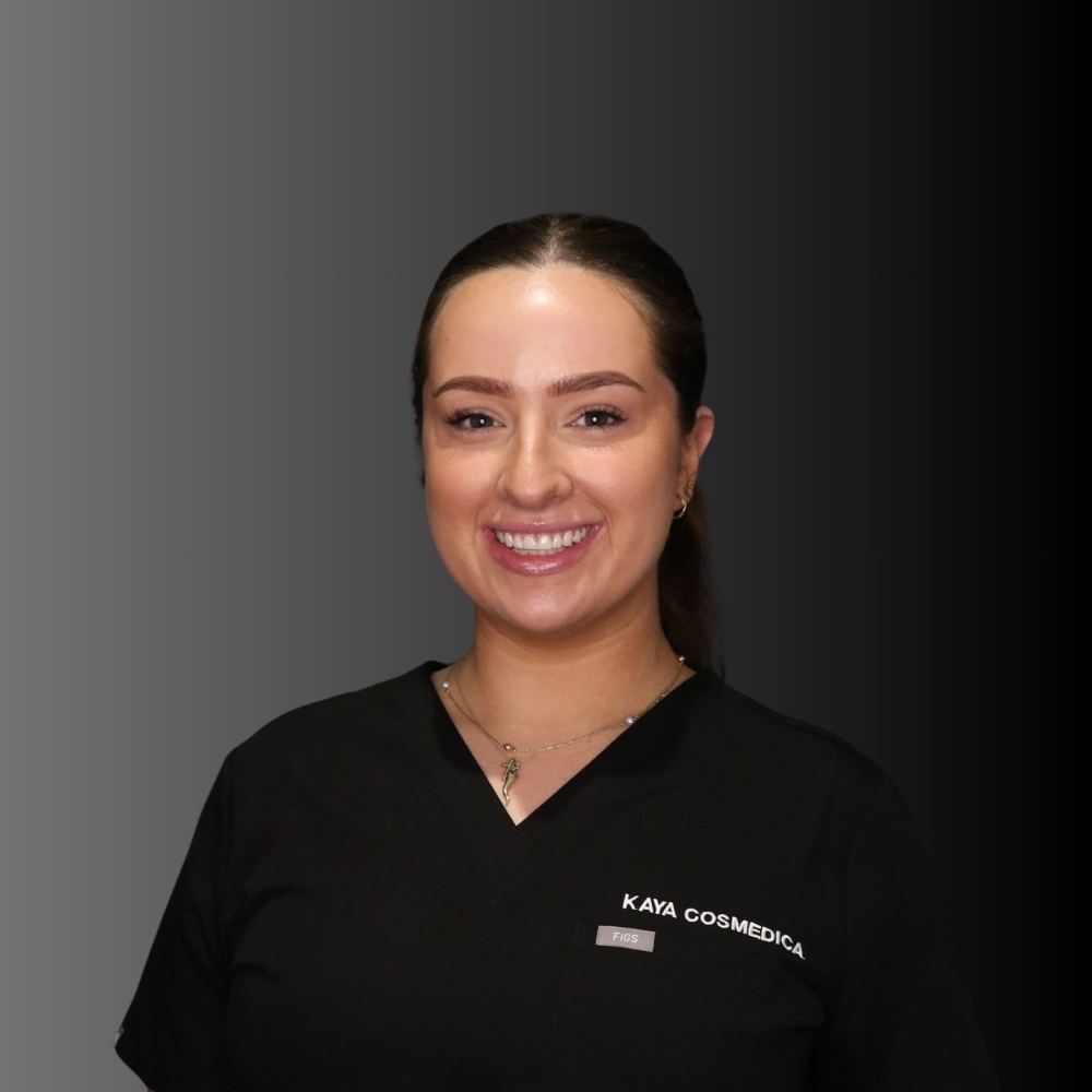 A woman with dark hair tied back, wearing a black top with "Kaya Cosmedica" written on it, smiles at the camera. The background features a black-to-gray gradient.