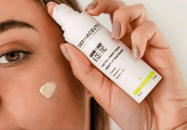 A person holds a 30ml bottle of Dermaceutic K Ceutic near their face, with a small amount applied to their cheek.